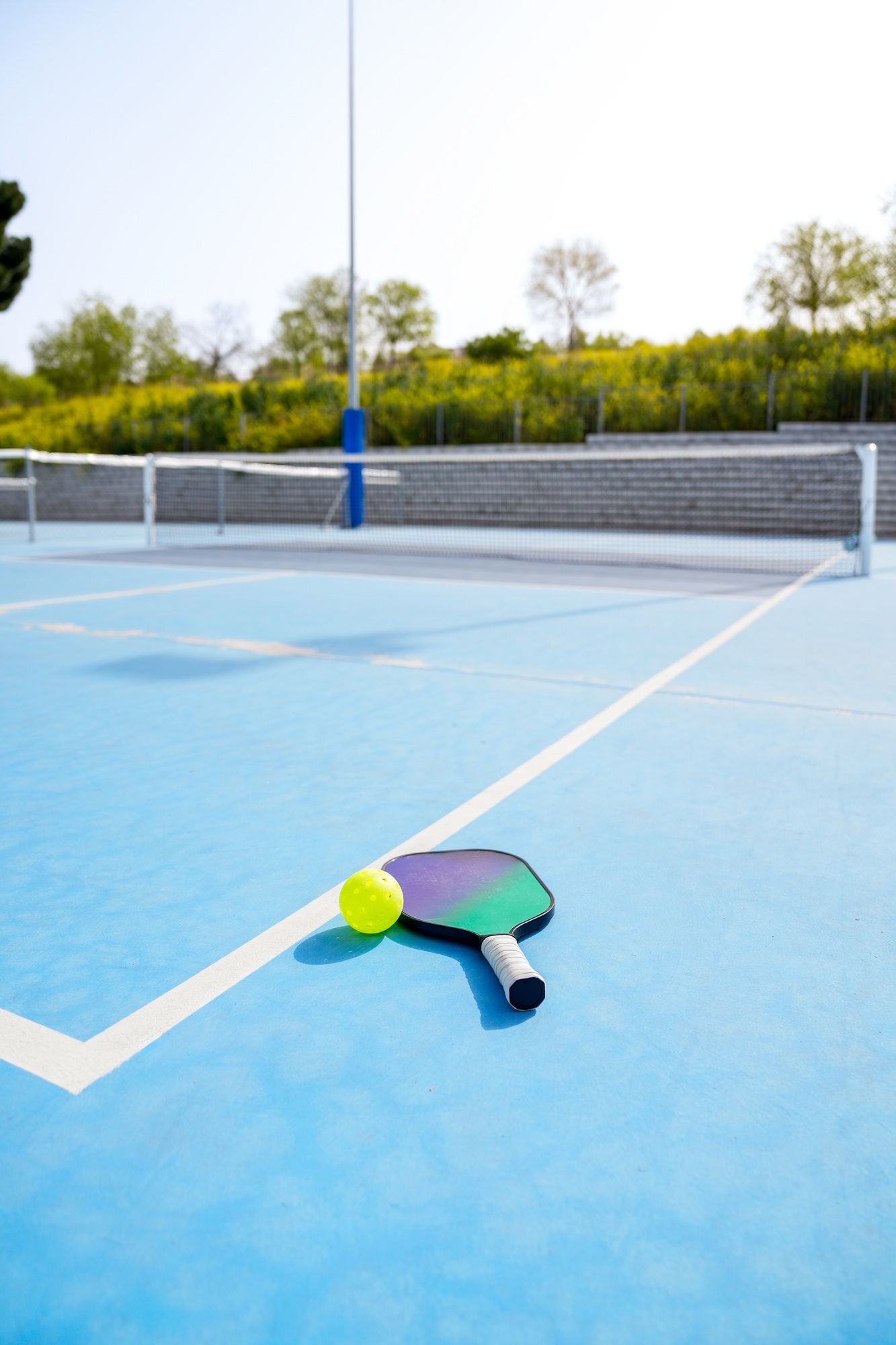 Pickleball paddle and ball on a blue court, ready for the next serve